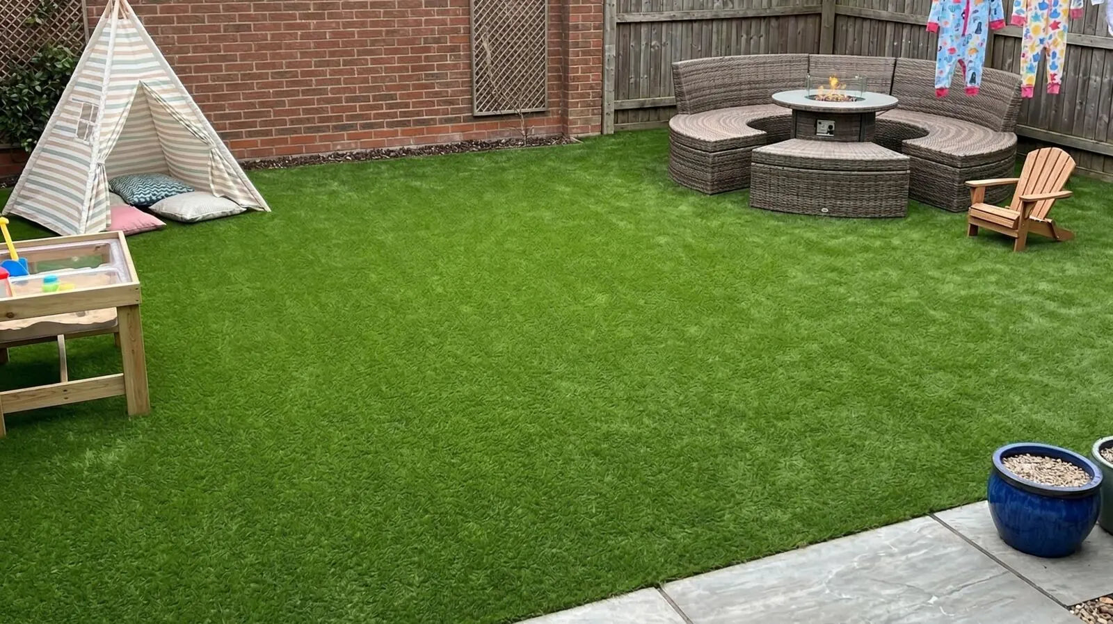 Family garden with artificial grass, a play teepee and a fire pit seating area