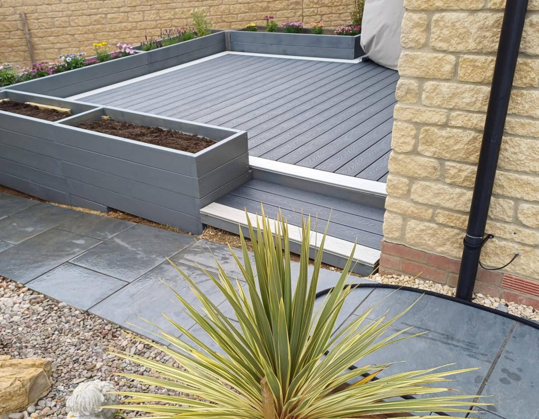A finished grey composite deck beside paving and a raised planter